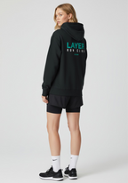 Layer Run Club black hoodie back view showing Layer Run Club print worn by female runner