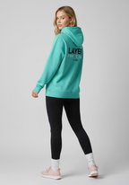 Female athlete wearing the green Layer Run Club hoodie, back view with Layer Run Club branding, styled for everyday training wear.
