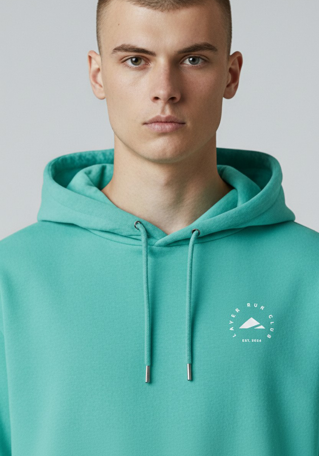 Close up of the Layer Run Club logo on green hoodie, showing clean branding and premium fabric texture.