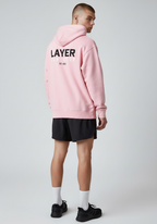 Male model wearing the Layer Run Club hoodie in pink, back view showing large Layer Run Club print.
