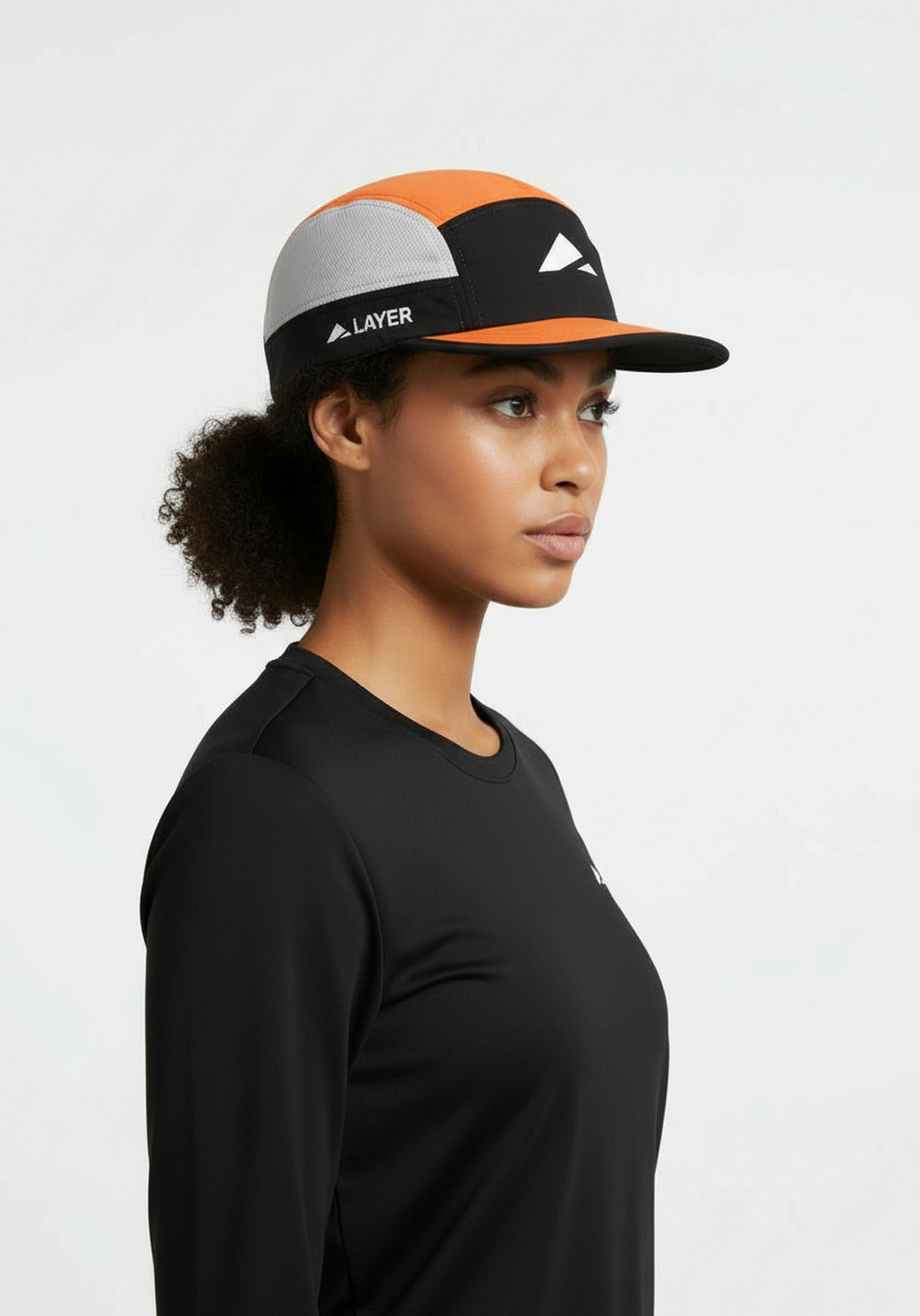 Layer running cap black and orange worn by female runner side view breathable performance running cap