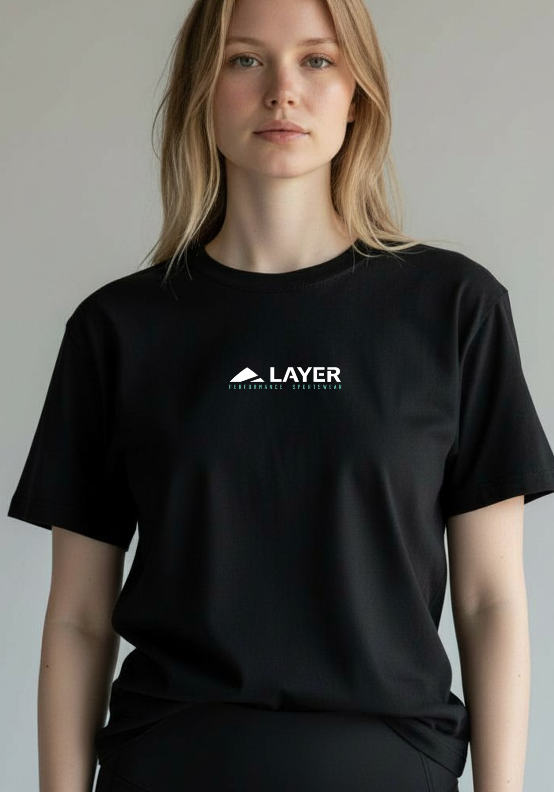 Woman shown from the waist up wearing a black Layer Performance Sport Signature Tee against a neutral background.