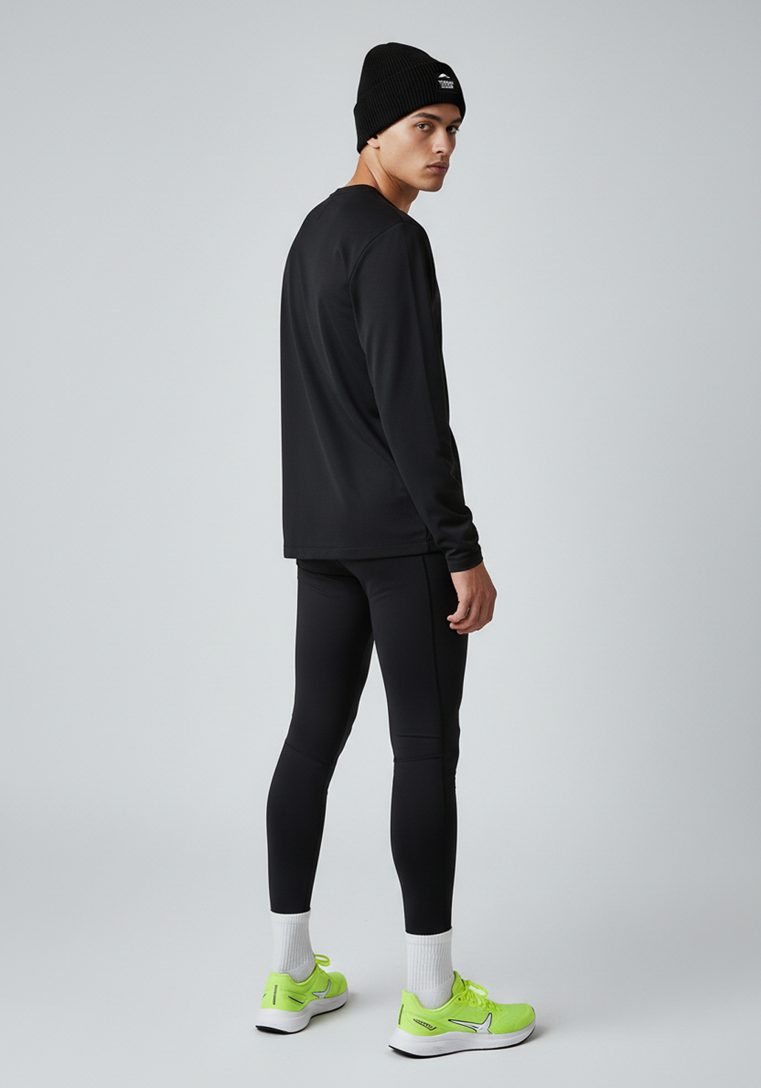 Model wearing black Layer Track Club beanie with tonal patch logo, rear view