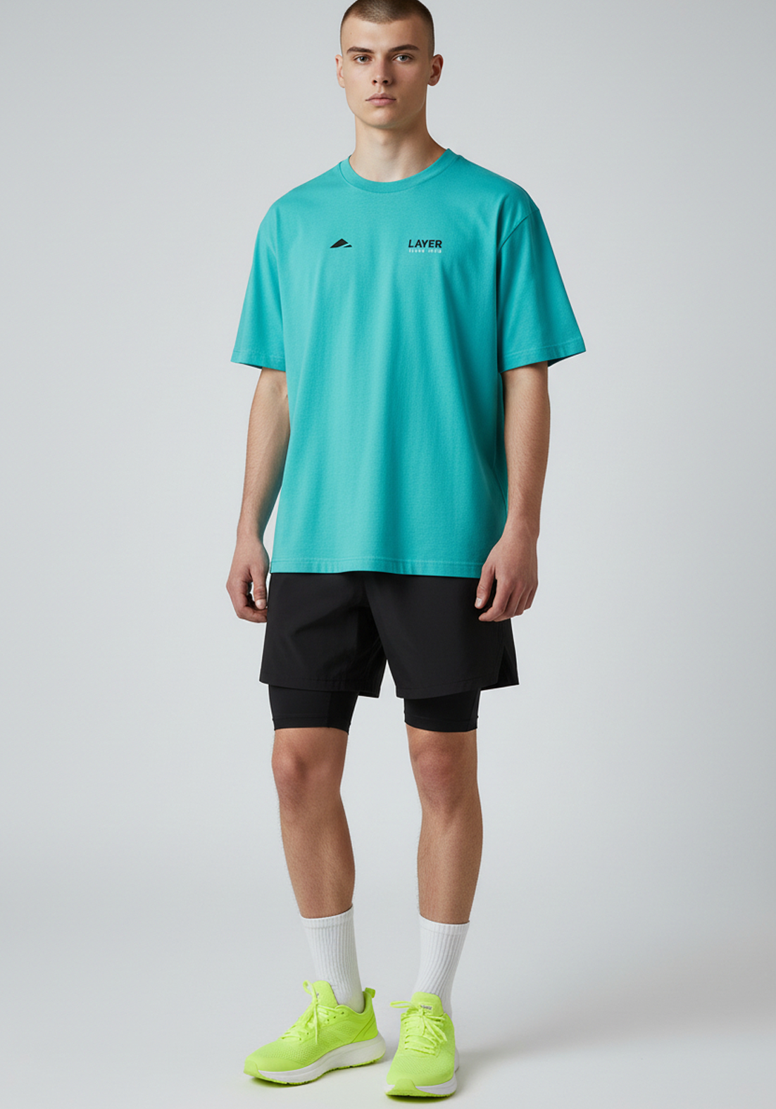 Full length view of the Layer Track Club Tee in teal styled with running shorts.
