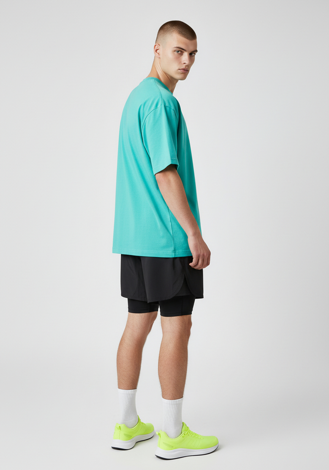 Side profile of the teal Layer Track Club Tee showing loose fit and soft drape.