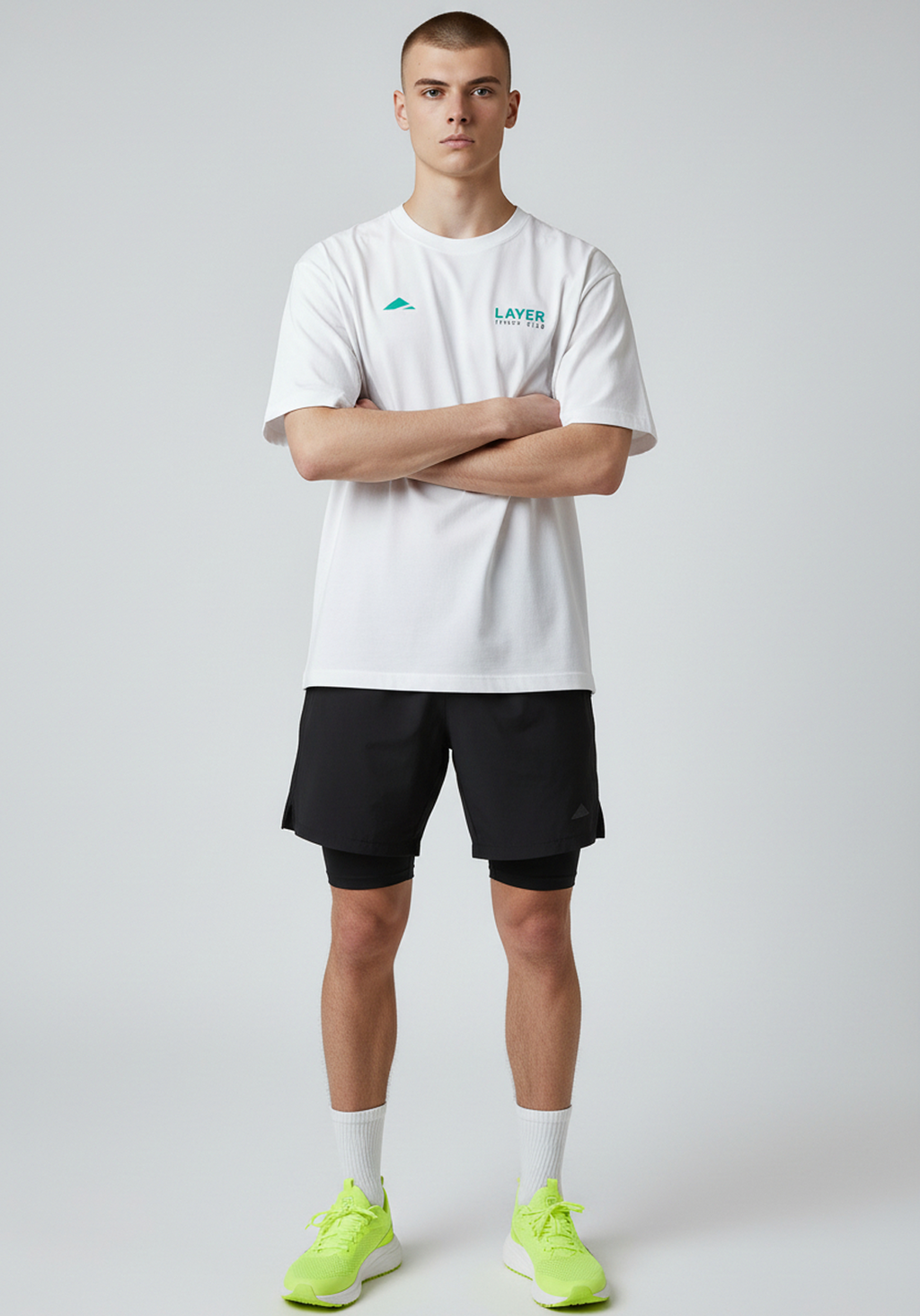 Model wearing white Layer Track Club tee with arms crossed front view