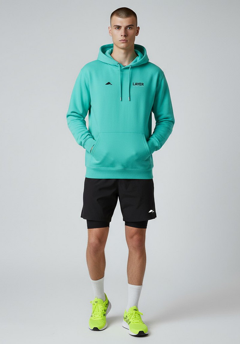 Layer Men’s Track Club Hoodie in teal – on-model front view showing relaxed athletic fit and kangaroo pocket design