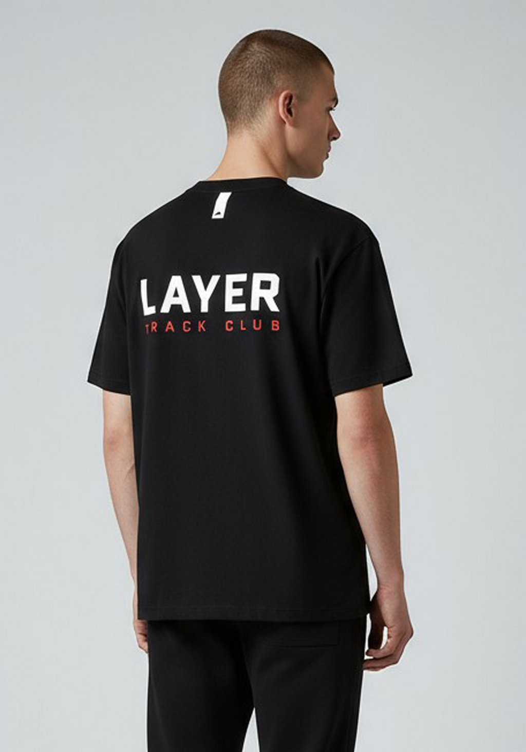 Layer Track Club Tee in black – angled back view showing bold LAYER TRACK CLUB back print in white and red