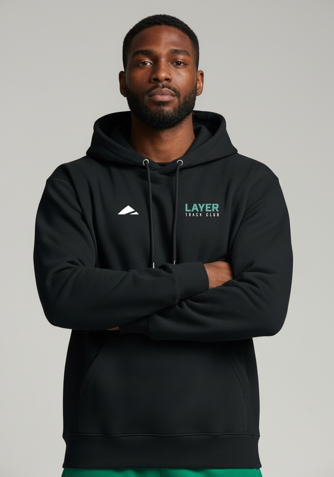 Front view of model wearing the Layer Track Club Hoodie in black with chest logo and drawstring hood