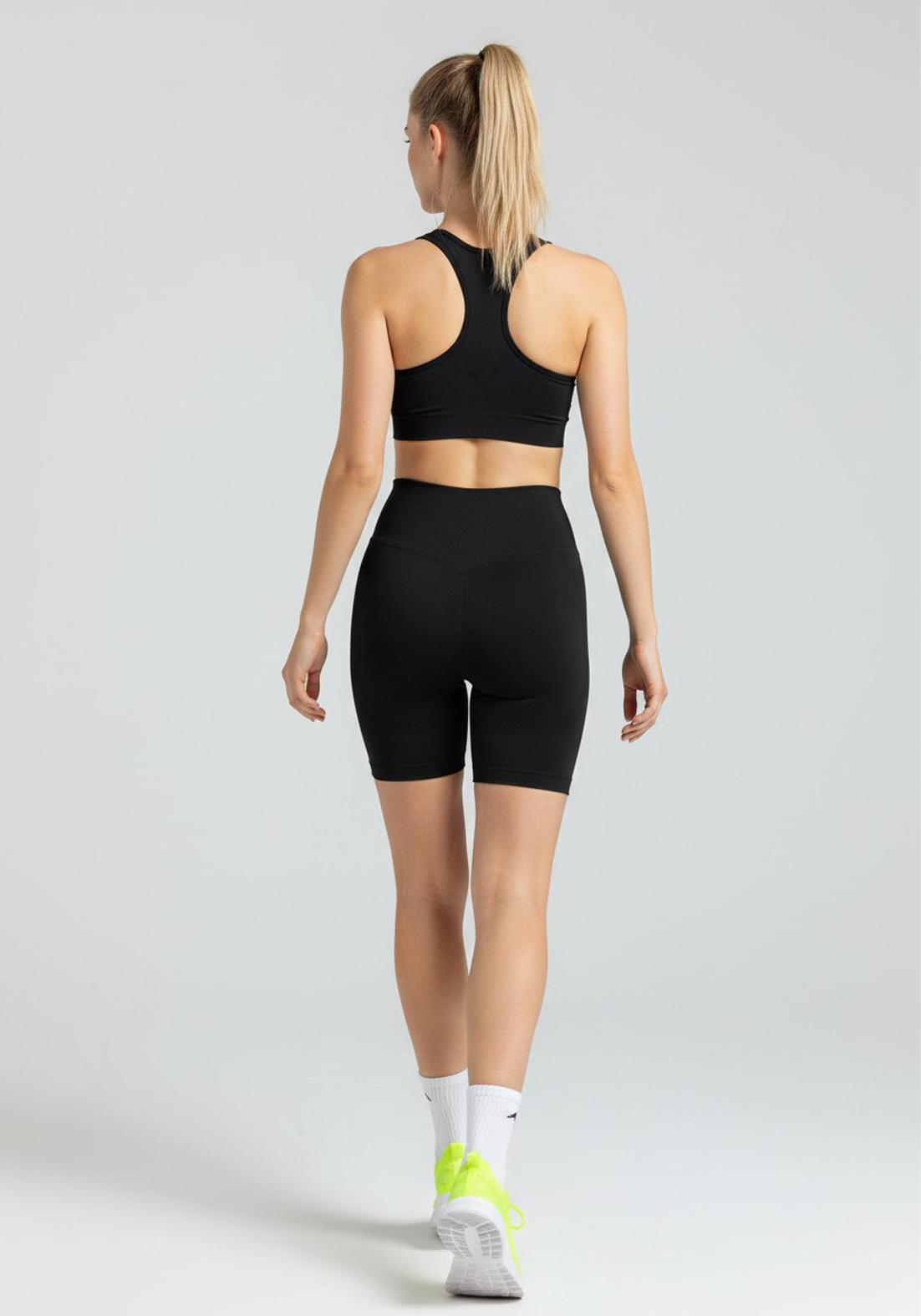Back view of women wearing black Layer Training Legging Shorts with high-rise waistband and supportive fit.