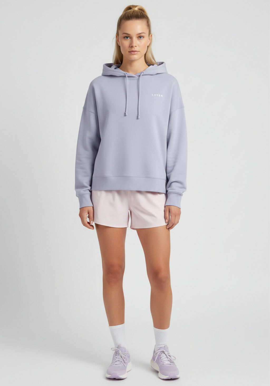 Women wearing lavender Layer FTR Graphic Hoodie styled with running shorts, angled front view