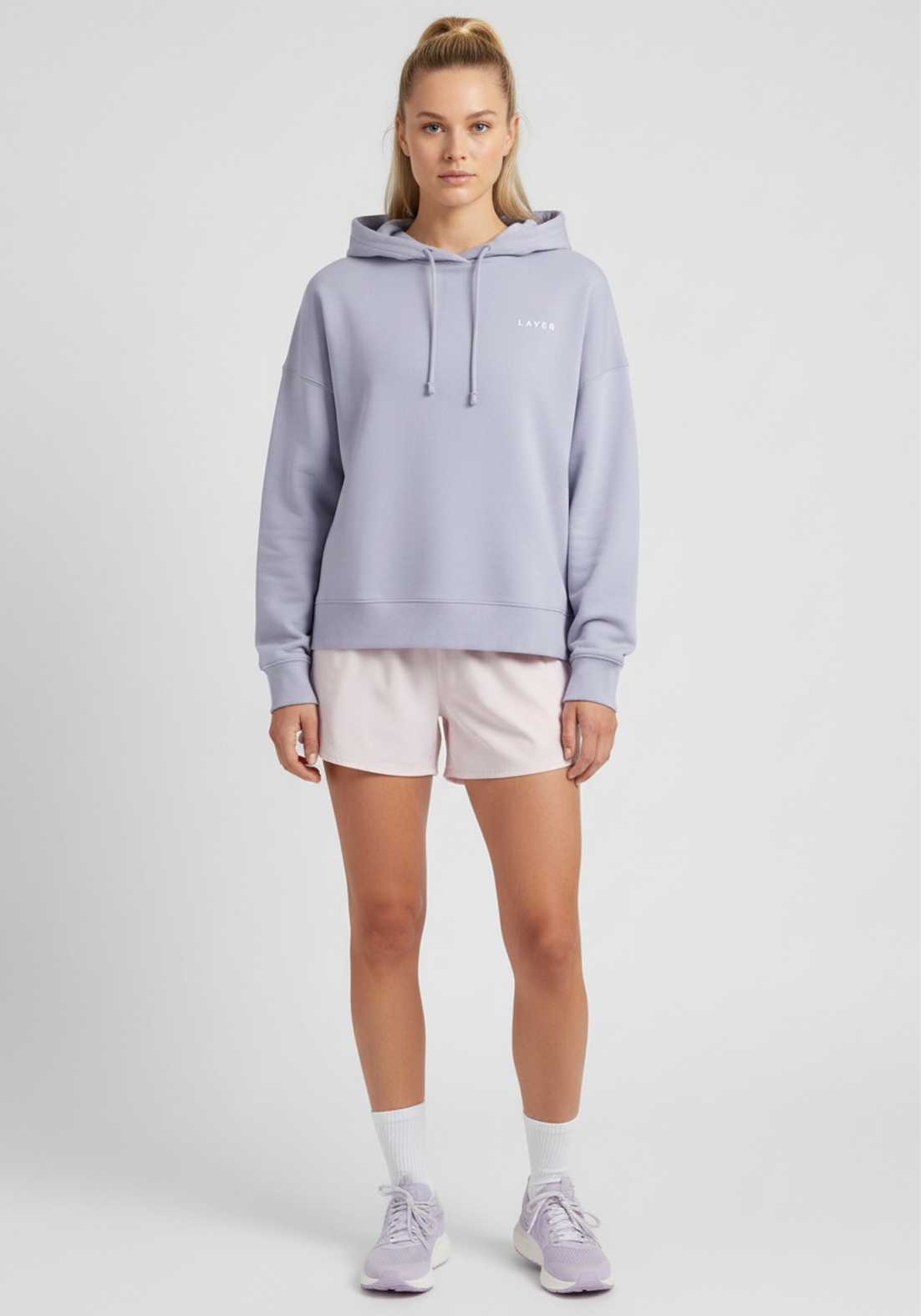 Women wearing lavender Layer FTR Graphic Hoodie styled with running shorts, angled front view