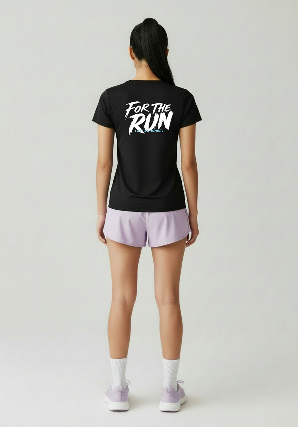 Back view of women wearing black Layer FTR Graphic Running Tee with ‘For The Run’ graphic, paired with lilac running shorts.